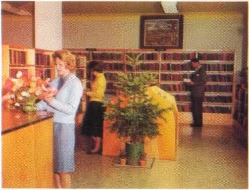 Interior of the Morwell Library in the 1960s. Well dressed, people browsing the bookshelves and reading books